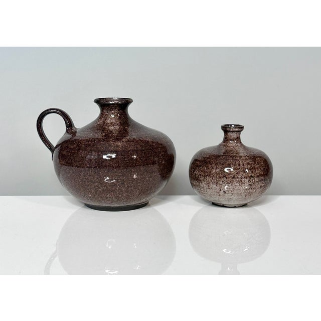 An impressive set of two studio ceramic art vessels including a jug and a vase, created by the renown ceramist duo Elli...