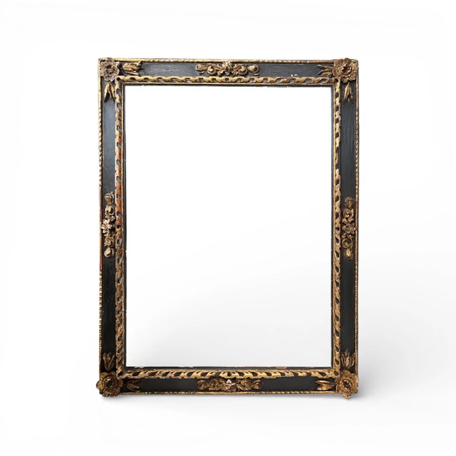 This 18th-century Italian carved frame features intricate ornamental carving brought into sharp relief by its blackened...