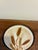 A mid-century teak serving tray by Goodwood, centered with a round ceramic tile trivet printed with a warm-toned wheat...