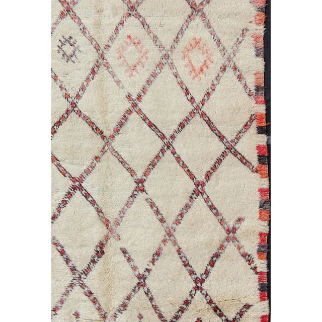 Measures: 6'5'' x 11'7''. Woven in light, creamy, hand-spun wool with muted red, gray and light charcoal symbols, this...