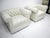 A pair of tufted white leatherette upholstered lounge chairs with rounded arms in the style of a 1970's Chesterfield...