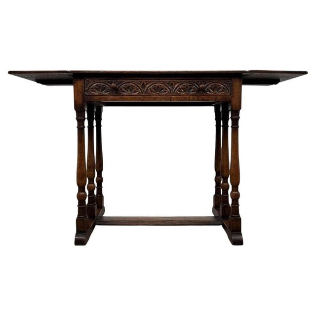 A handsome early 20th-century English drop-leaf side table, finely crafted from oak and distinguished by its versatile...