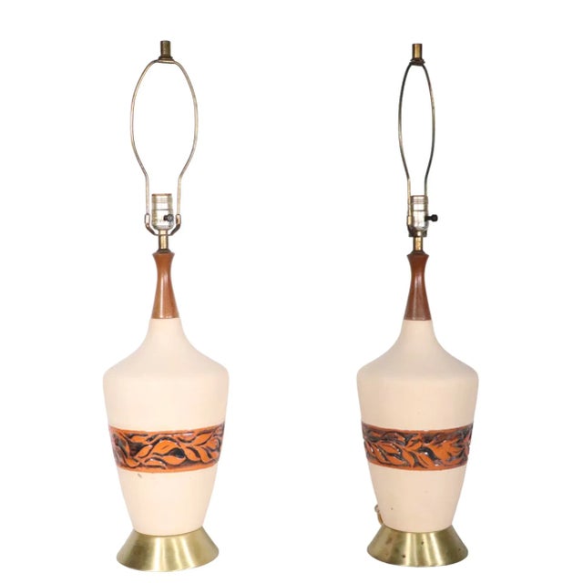 Pair Mid Century table lamps, with ceramic bodies, wood finial tops, and spun metal bases. The ceramic bases show minor...