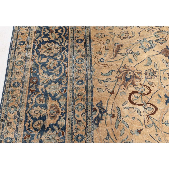 An early 20th century Persian Tabriz antique rug, the caramel field with a whimsical overall design of swirling leafy...