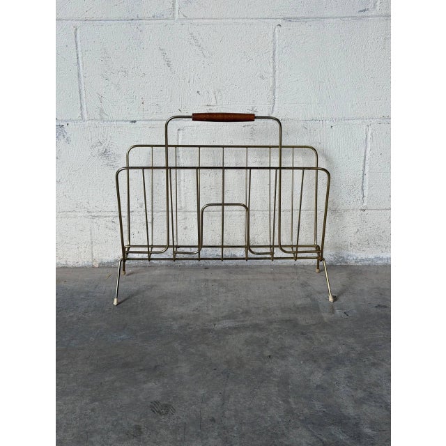 This sleek brass wire magazine holder features a convenient integrated wooden handle and an open-frame silhouette. Its...