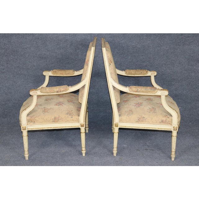 A graceful and beautifully coordinated pair of paint-decorated Louis XVI-style bergère armchairs, distinguished by their...