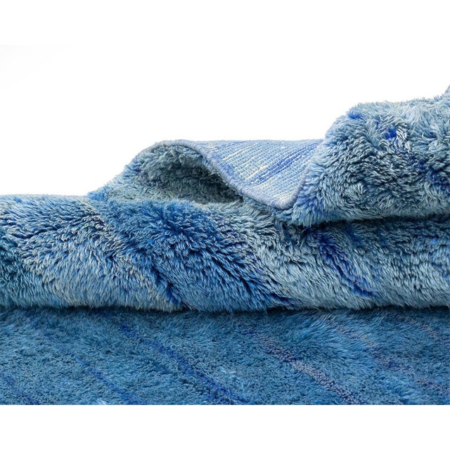 Deep sapphire dissolves gradually into soft sky blue, an ombré wash that gives this rug the calm, immersive quality of...