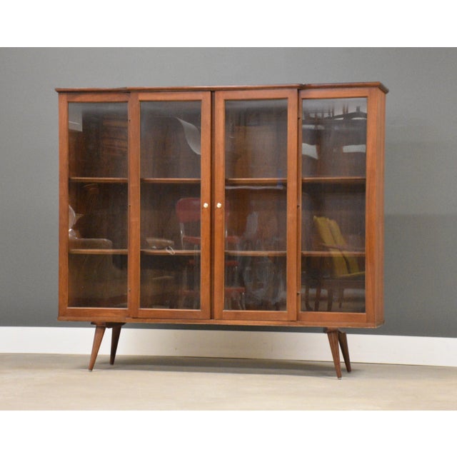 A mid century modern walnut bookcase with two glass doors. Made in the USA. Circa 1960’s. Original finish in very good...