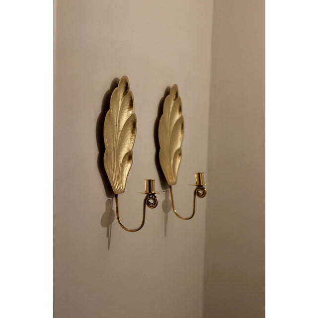 Made in Sweden. Two exquisite leaf shape brass candle sconces from the Mid Century era, meticulously handcrafted with a...