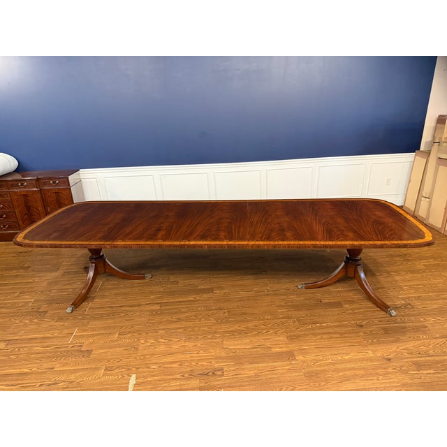 This is a classic mahogany dining table with delicately shaped double scalloped corners. The top has a swirly crotch...