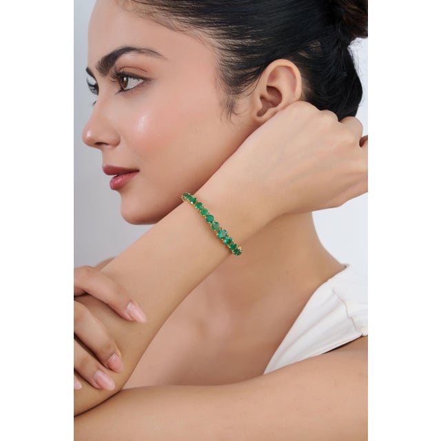 This statement tennis bracelet showcases 12.9 carats of natural round-cut emerald, set in 18k yellow gold. Each emerald is...