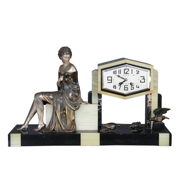An exceptional and difficult to find Art Deco Garniture Clock Set depicting a young lady looking down at birds below. Set...