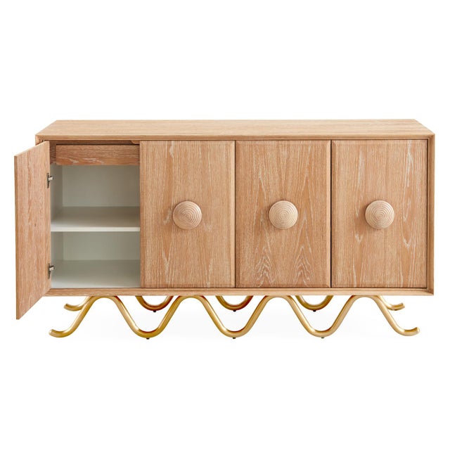 Commanding scale and simple form with turned oak handles and luxe velvet-lined drawers resting on a sinuous brushed brass...
