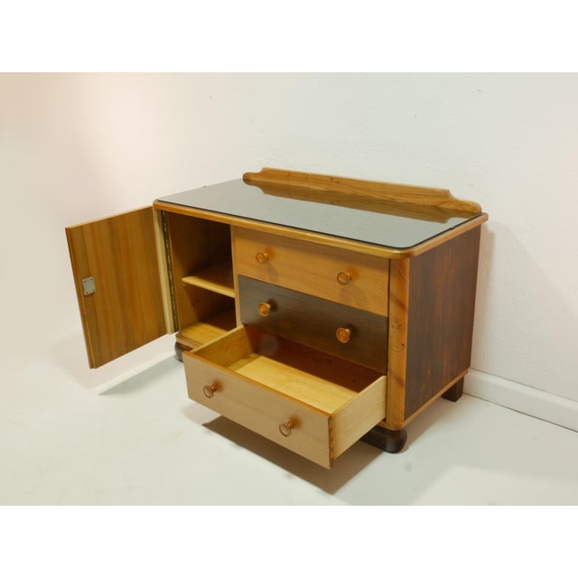 This stylish vintage chest of drawers from the 1950s impresses with its clean lines and charming details. A glass top...