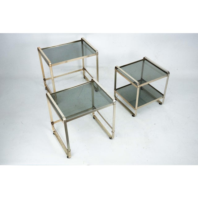 Elegant set of three nesting side tables crafted in lightly gilded aluminum with glass tops, produced in Italy during the...