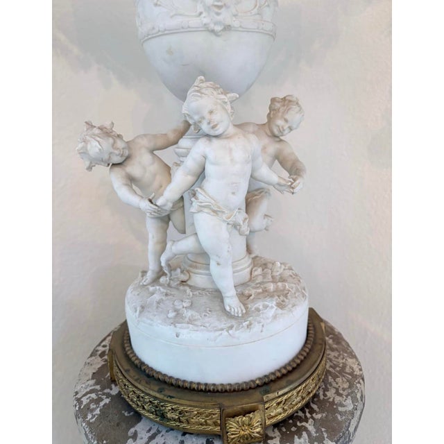 Elaborate antique porcelain and gilt-metal centerpiece featuring three finely modeled putti surrounding a classical urn...