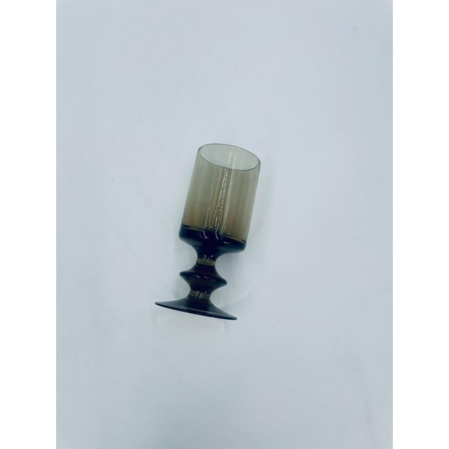 A Mid-Century Modern wine goblet from the 1970s, crafted from high-quality glass. The smoked goblet features a cylindrical...