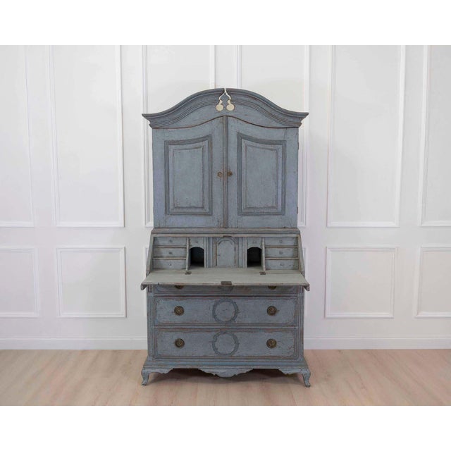 Made in Scandinavia in the eighteenth century, this two-part bureau has a blue painted finish and fine carvings. The two-...