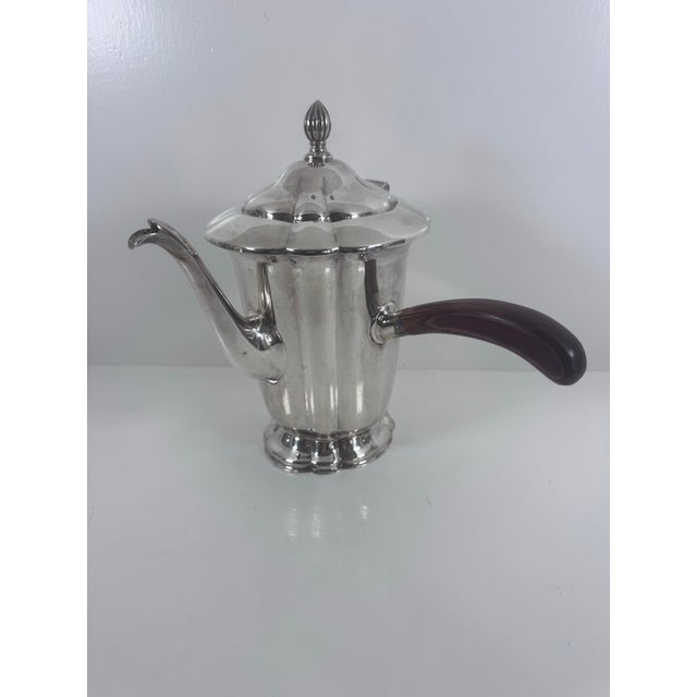 A sculptural vintage coffee pot by Forbes Silver Co., with a curved spout, distinctive scalloped lid, finial, and dark...