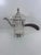 A sculptural vintage coffee pot by Forbes Silver Co., with a curved spout, distinctive scalloped lid, finial, and dark...