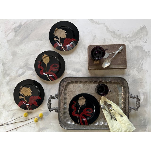 Striking vintage set of four Fitz and Floyd black floral plates, dated 1979. These plates feature bold, stylized botanical...