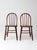 A pair of vintage Windsor style chairs with classic spindle backs and gently contoured seats, crafted in warm wood with a...