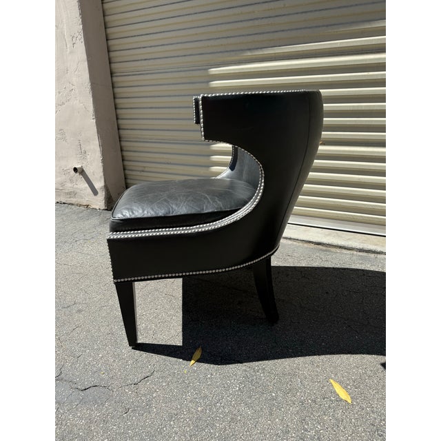 A handsome black leather barrel chair by Lexington Furniture, featuring a sculptural wraparound silhouette accented with...