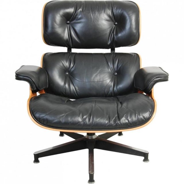 Charles Eames Lounge chair upholstered in black leather and with a shell of cherry wood. The chair appears in good...