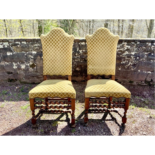 A set of six Jacobean style carved walnut dining side chairs with a barley twist stretchers, scalloped apron, sculpted...