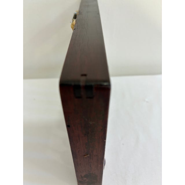 A compact vintage Chinese suanpan abacus crafted from dark reddish-brown wood with 11 rods and traditional wooden counting...