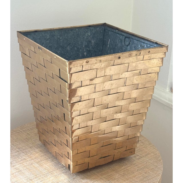 Brass waste basket or planter. Woven brass bands make up the exterior. Removeable Zinc metal insert with pulls. On 4 small...