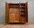 A 1930s Art Deco wardrobe in figured walnut veneer, with three shaped doors and decorative metal handles. Inside are...