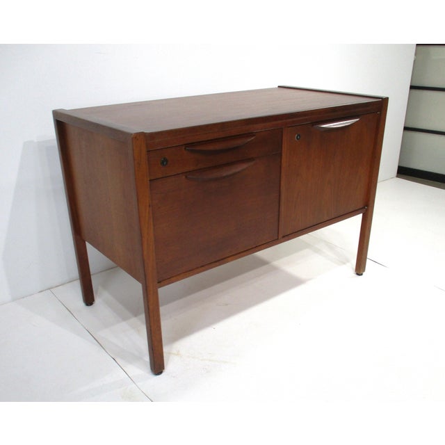A very well crafted walnut smaller sized credenza with a small upper divided drawer and larger file styed drawer and to...