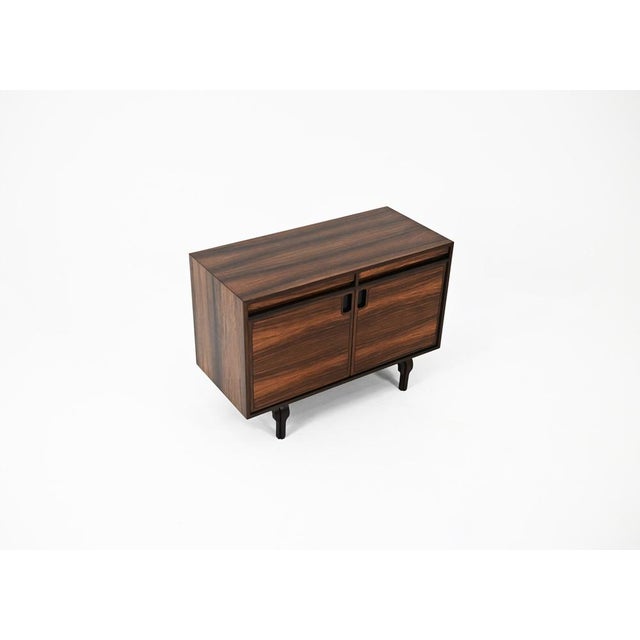 Wooden sideboard with two drawers and two doors, containing a glass shelf, by Renato Magri. Signs of wear consistent with...