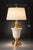 A striking tall Hollywood Regency table lamp featuring a sculptural milk glass urn body with polished brass hardware and...