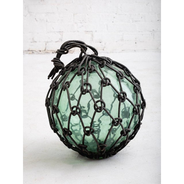 Antique Japanese fishing float crafted with hand blown green glass and knotted rope. Two available sold separately.