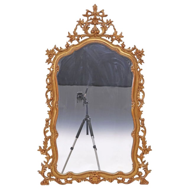 French Louis XV style giltwood wall mirror, 20th century, featuring a shaped frame with a pierced floral crest and...