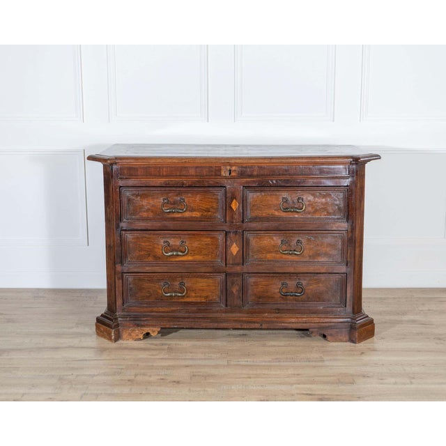 A distinguished 17th-century Tuscan chest of drawers, crafted in solid and veneered walnut with elegant maple thread...
