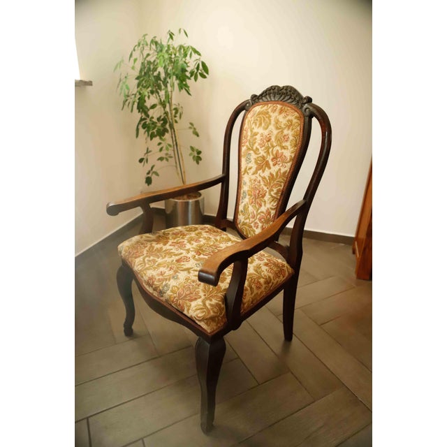 This antique carver armchair dates from approximately 1890–1920 and features a Queen Anne Revival design with Chippendale...