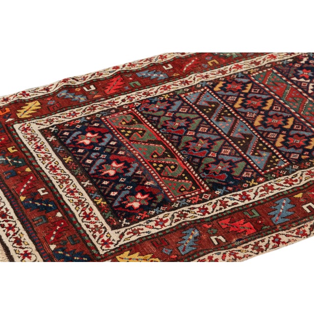 Beautiful antique Kazak hand-knotted wool runner with a red field, blue and ivory accents in a gorgeous all-over geometric...
