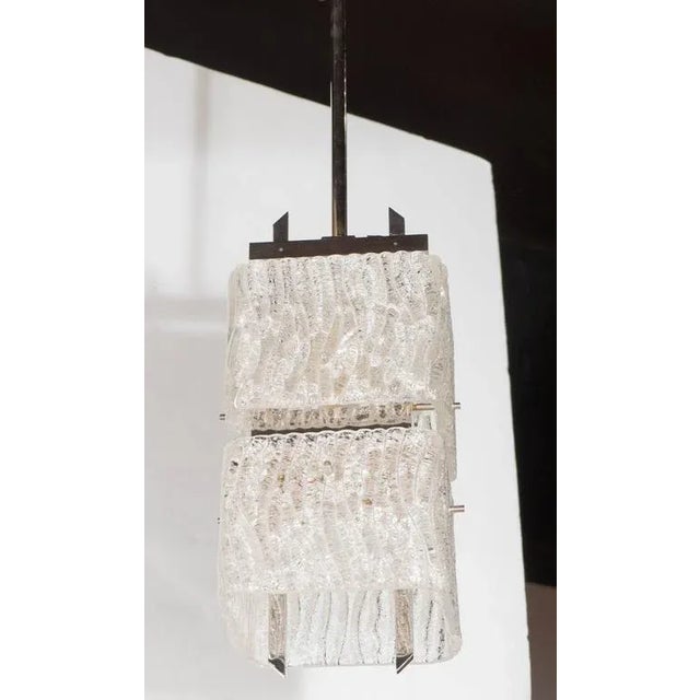 A Mid-Century Modernist two-tier textured glass pendant. Two round-edged square shades are supported by a chrome frame and...