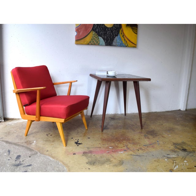 This is a coffee table from the 1950s. It features black ceramic tiles on the surface. The tapered legs are made of...