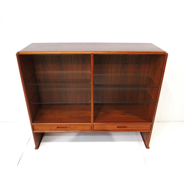 A very well-crafted Mid Century teak wood bookcase with four sliding glass doors and four adjustable glass shelves. This...