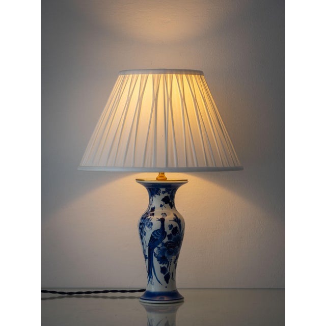 A Royal Delft vase, hand-painted in the Netherlands and mounted as a table lamp, its body carrying a long-tailed bird...