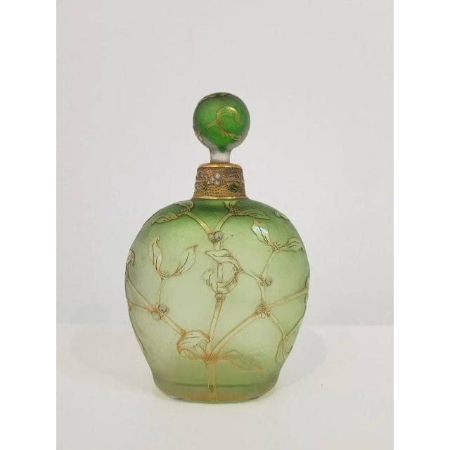 Beautiful and elegant bottle with stopper by Daum, Nancy. France late 19th century. Light green with flowers in relief all...