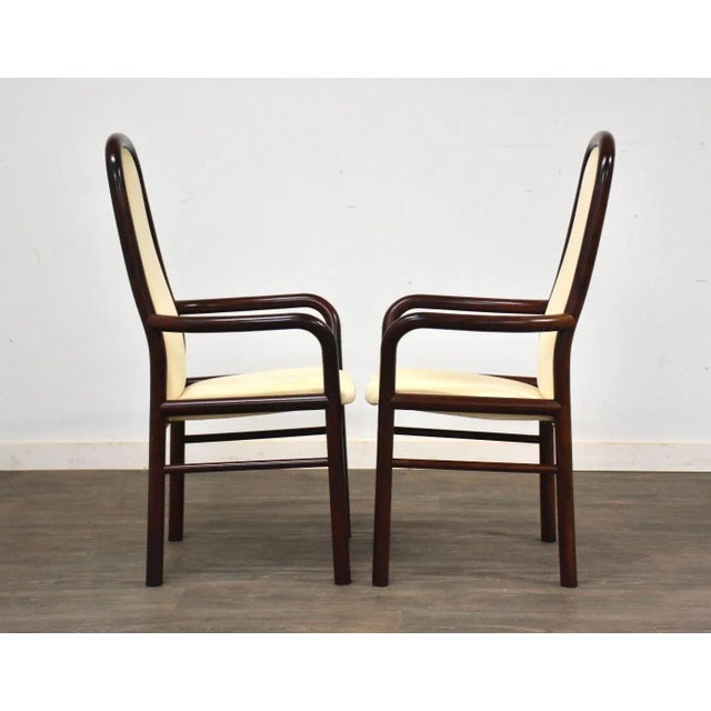 A pair of mid century modern rosewood color dining chairs with off white fabric made by Boltinge. Seat height is 17”....