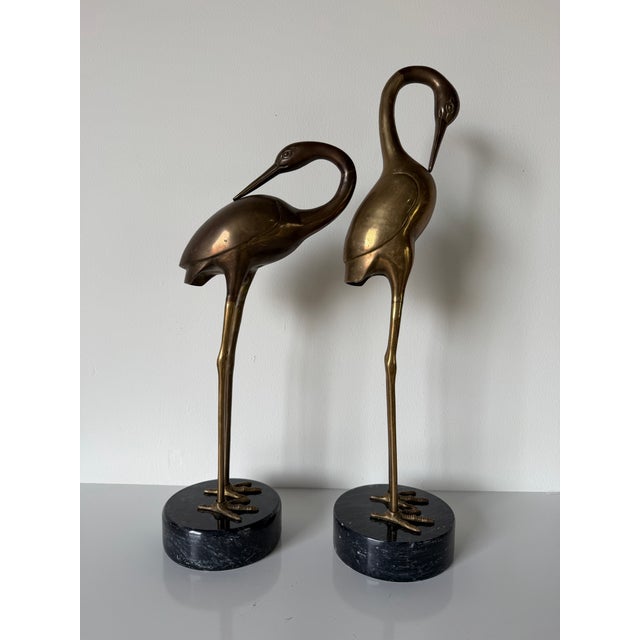 Striking vintage pair of life-size brass crane sculptures featuring elegant elongated necks, finely detailed beaks, and...