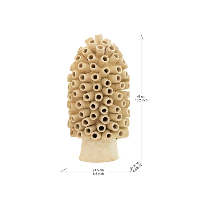 Dozens of hollow terracotta cylinders cluster together into a rounded, coral-like mass, each tube catching light and...