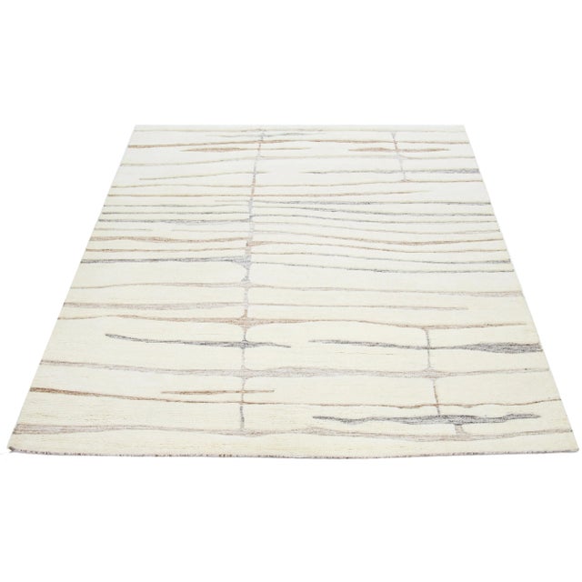 This hand-knotted Moroccan-style wool rug features a beautiful modern design with a natural ivory background. It showcases...