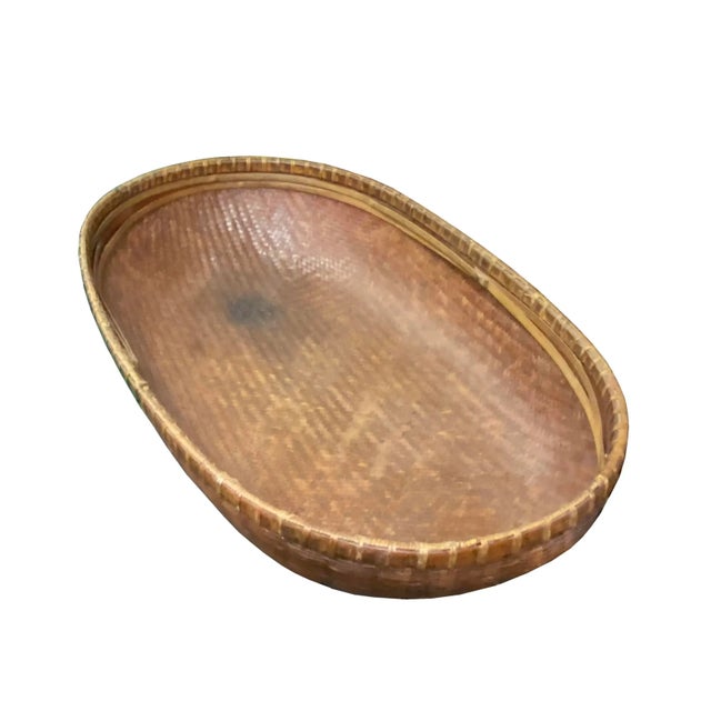 This is a traditional oriental rattan basket tray in a long oval shape. It has a nice brown color with a wear-out patina....